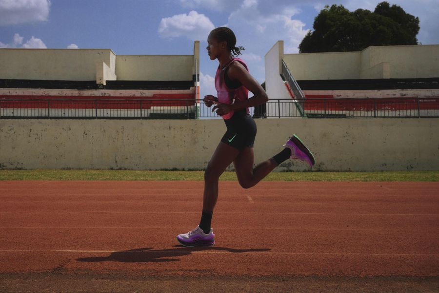 Faith Kipyegon court sur une piste, en tenue rose et noire