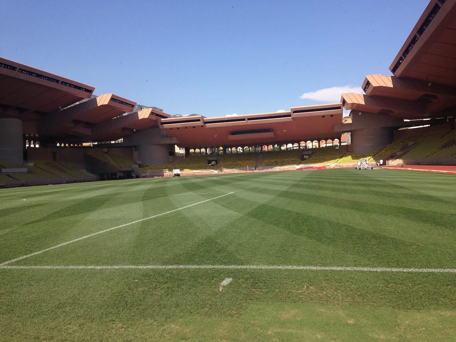 La pelouse et les tribunes du stade Louis-II, à Monaco, sous un ciel bleu.