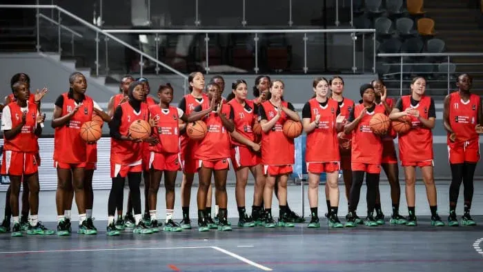 Female players in red jerseys applaud during the camp