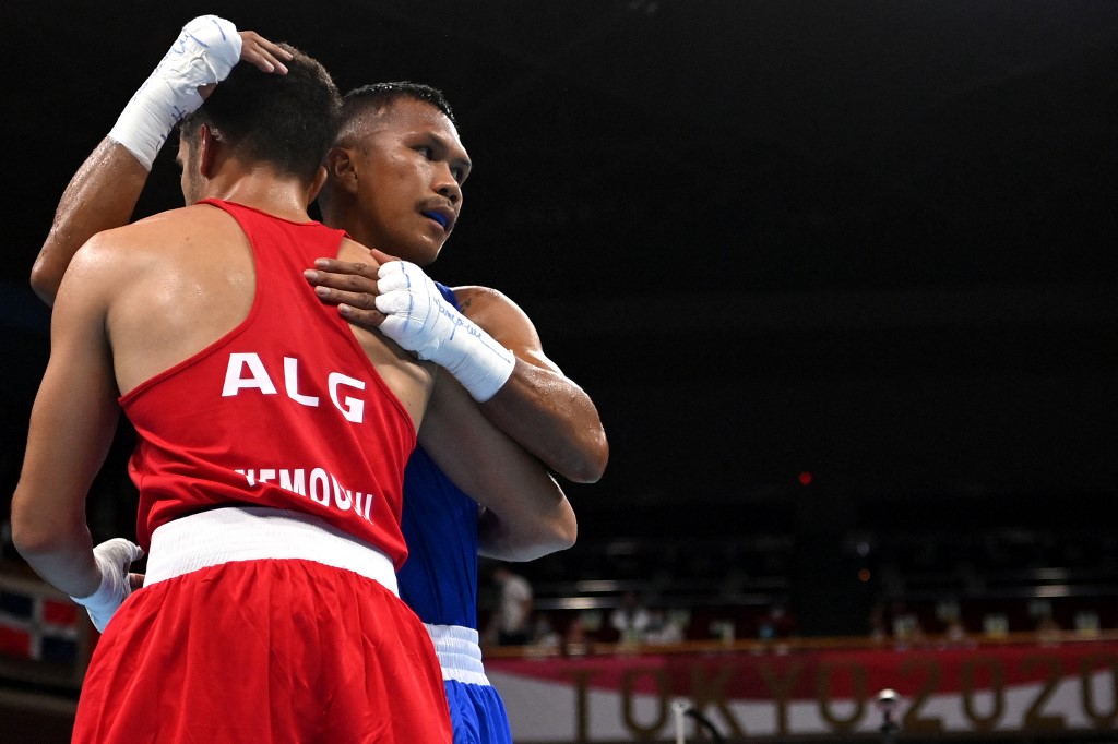 Algeria's Younes Nemouchi (red) and winner Philippines' Eumir Marcial hug at the end of their men's middle (69-75kg) preliminaries round of 16 boxing match during the Tokyo 2020 Olympic Games at the Kokugikan Arena in Tokyo on July 29, 2021. (Photo by Luis ROBAYO / various sources / AFP)