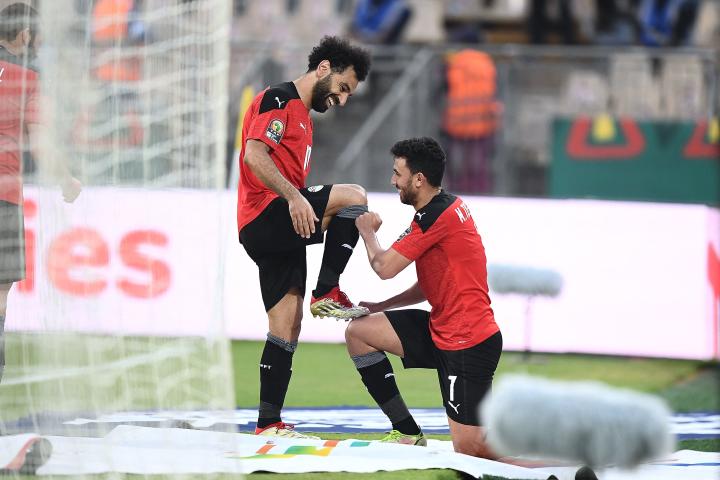 Egypt's midfielder Mahmoud 'Trezeguet' Hassan (R) celebrates with Egypt's forward Mohamed Salah after scoring his team's second goal during the Africa Cup of Nations (CAN) 2021 quarter-final football match between Egypt and Morocco at Stade Ahmadou Ahidjo in Yaounde on January 30, 2022. (Photo by CHARLY TRIBALLEAU / AFP)
