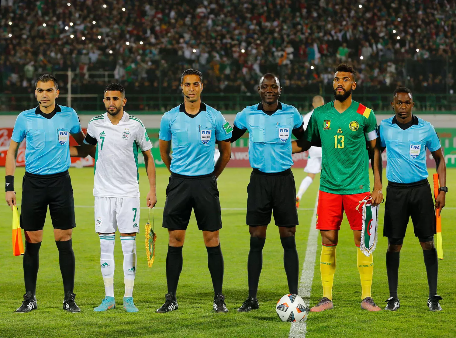 Algérie-Cameroun (1-2). L'arbitre Bakary Gassama (3e à partir de la droite) entouré des deux capitaines et de ses assistants.