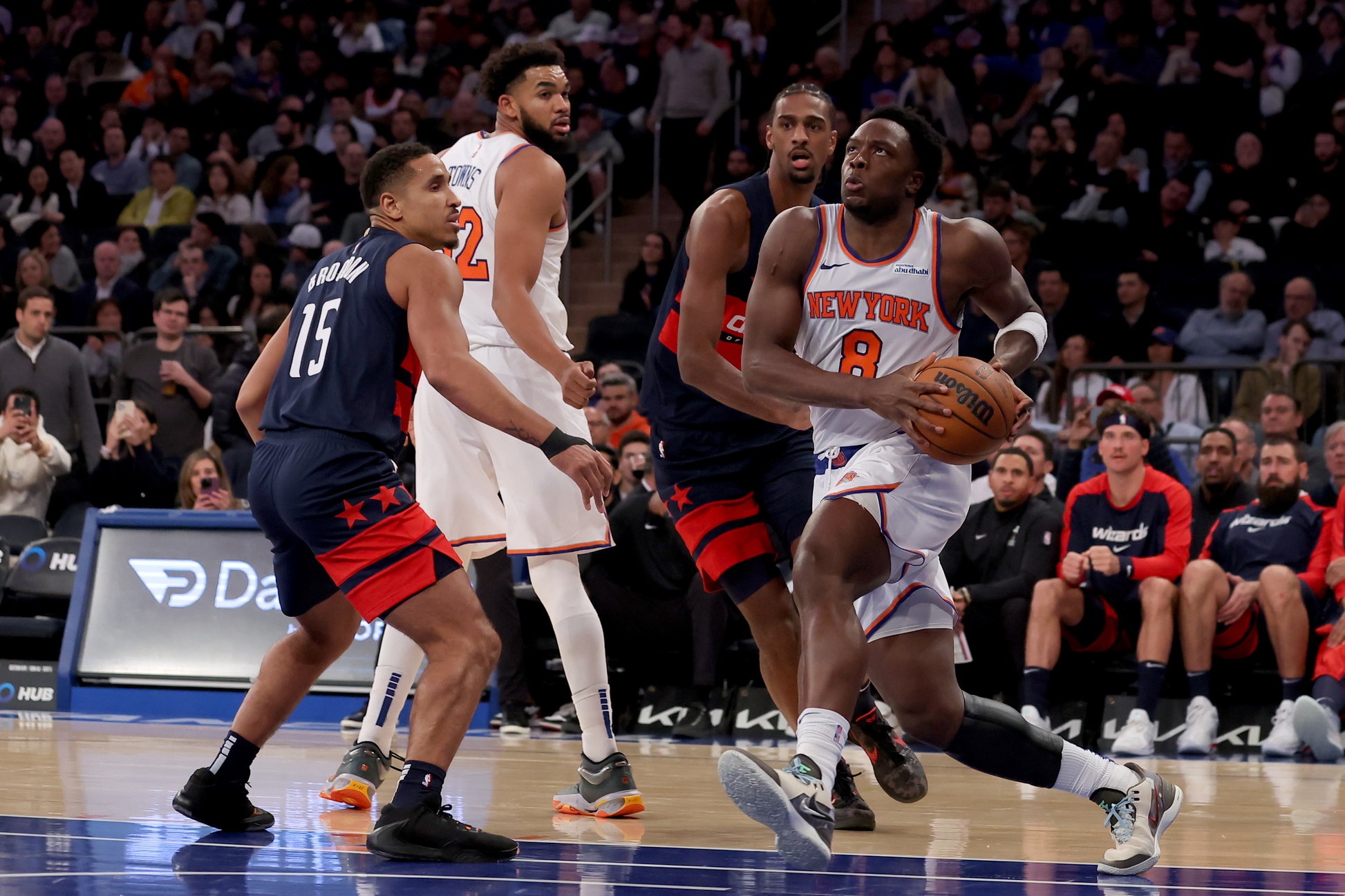 Nov 18, 2024; New York, New York, USA; New York Knicks forward OG Anunoby (8) drives to the basket against Washington Wizards guard Malcolm Brogdon (15) and forward Alexandre Sarr (20) during the third quarter at Madison Square Garden. Mandatory Credit: Brad Penner-Imagn Images