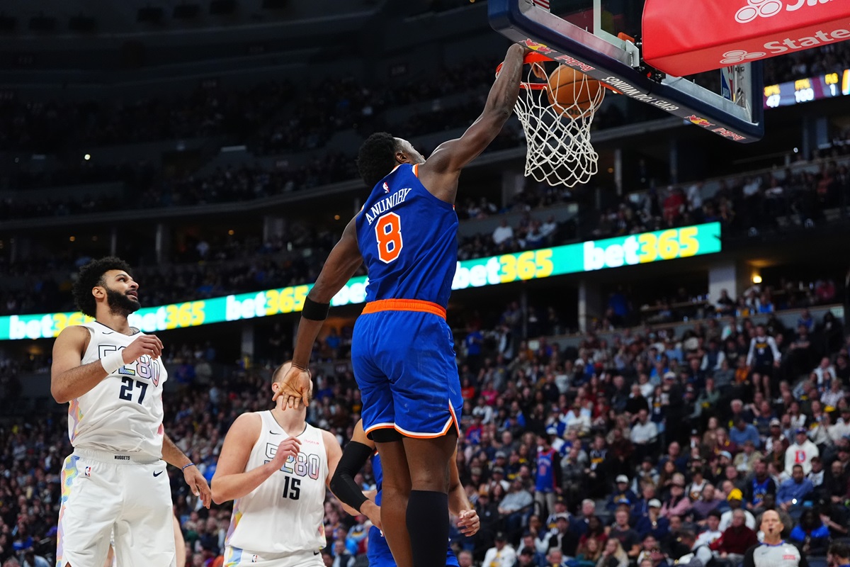 Nov 25, 2024; Denver, Colorado, USA; New York Knicks forward OG Anunoby (8) finishes off a basket past Denver Nuggets guard Jamal Murray (27) and center Nikola Jokic (15) in the second half at Ball Arena. Mandatory Credit: Ron Chenoy-Imagn Images