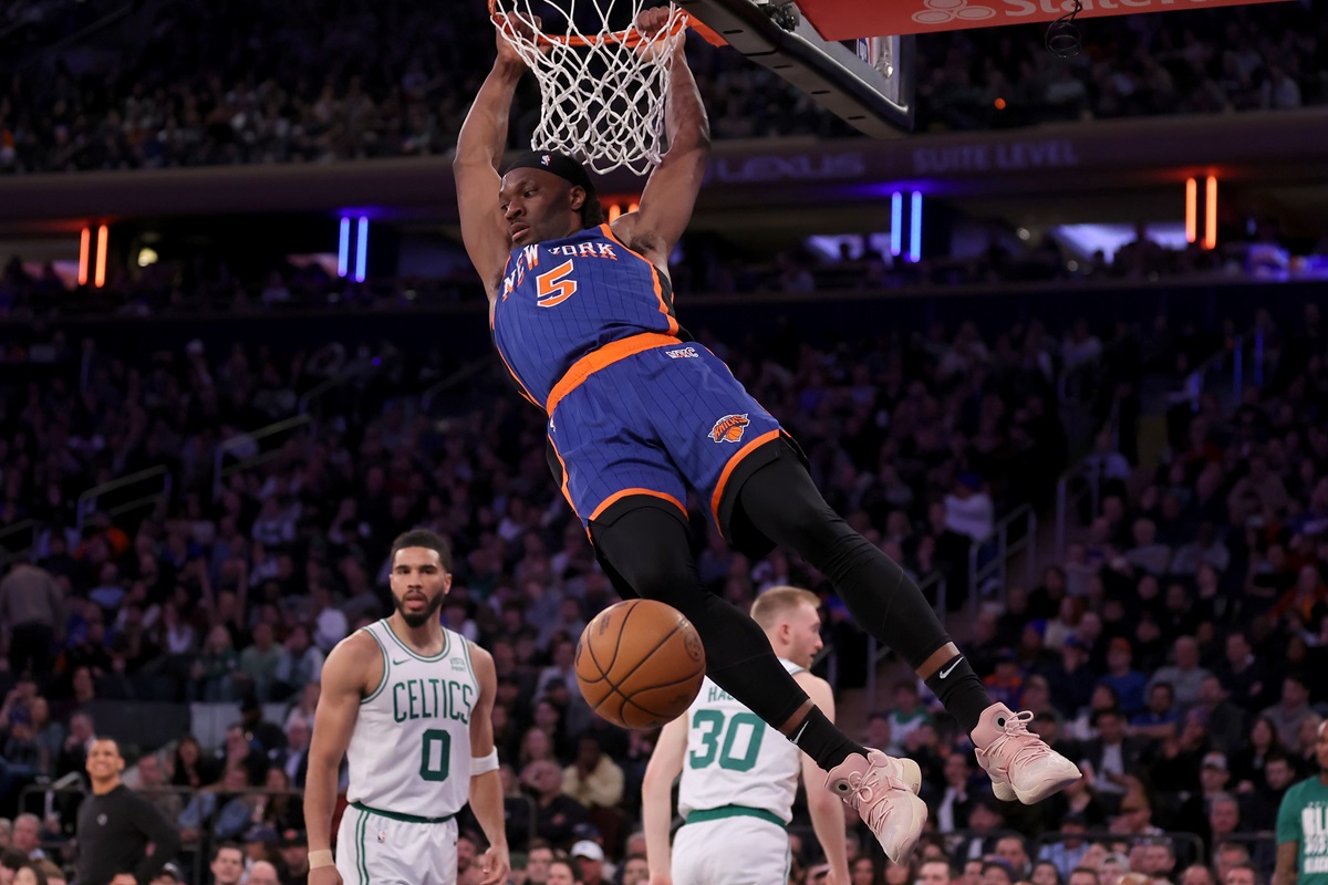 Feb 24, 2024; New York, New York, USA; New York Knicks forward Precious Achiuwa (5) hangs on the rim after a dunk against Boston Celtics forwards Jayson Tatum (0) and Sam Hauser (30) during the third quarter at Madison Square Garden. Mandatory Credit: Brad Penner-USA TODAY Sports