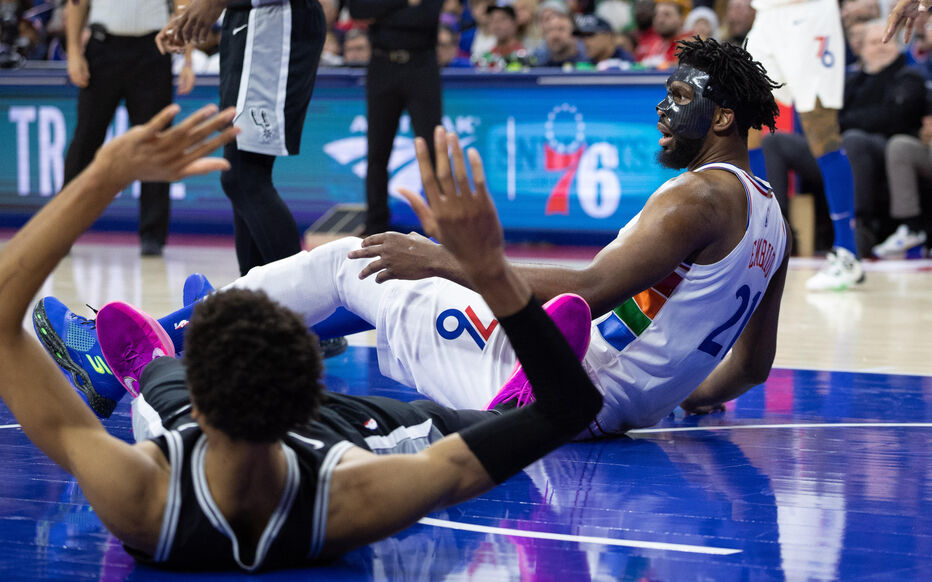 Dec 23, 2024; Philadelphia, Pennsylvania, USA; Philadelphia 76ers center Joel Embiid (21) and San Antonio Spurs center Victor Wembanyama (1) fall to the floor after colliding during the second quarter at Wells Fargo Center. Mandatory Credit: Bill Streicher-Imagn Images/Sipa USA