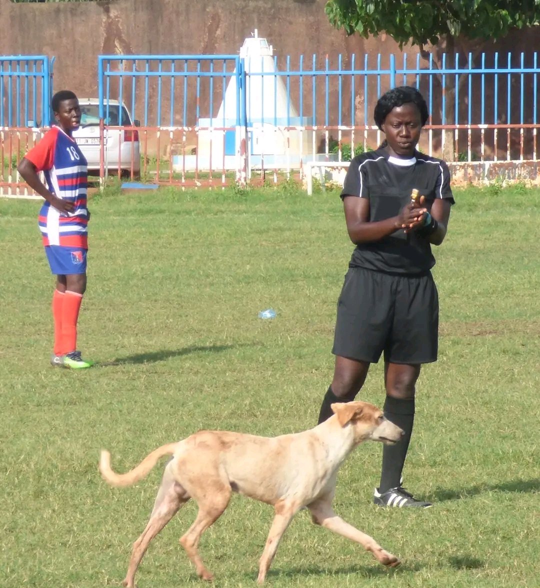 Jacqueline Nikiéma suppliant un chien de changer de terrain de jeu lors d'un match de Ligue 1 féminine du Burkina Faso.